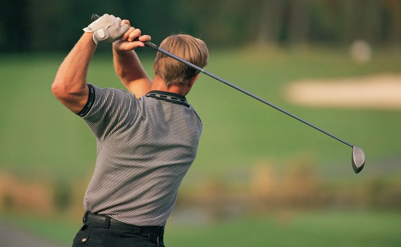 A male golfer swinging a golf club on a green course, representing active patients seeking sports chiropractic care in Temecula, CA.